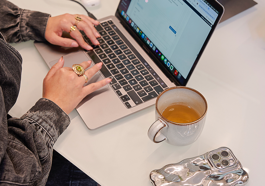 Personne travaillant sur un bureau avec une tasse de thé à côté